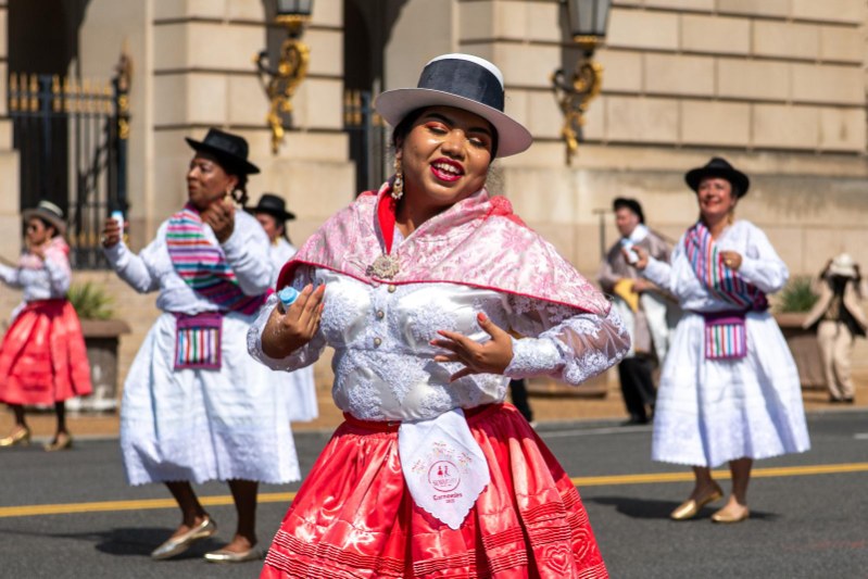 Sumaj Tusuy dancer performing in traditional red and pink costume